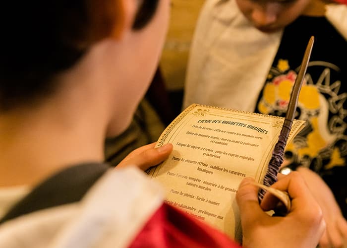 Enfant lisant un grimoire de baguettes magiques lors d'un anniversaire escape game